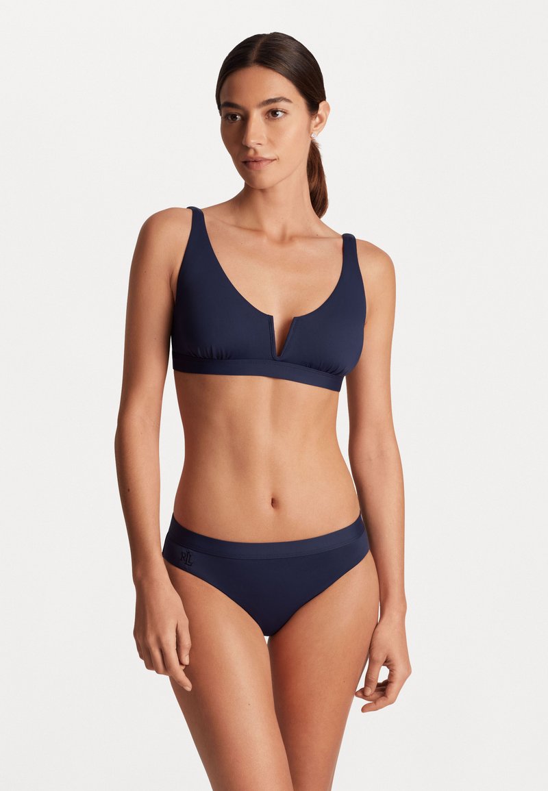 Tumesinine bikiin, millel on V-kujuline disain, laiad õlapaelad ja veniv kangas. Alumine osa on sobiva vöökohtadega, millel on õrn logo.