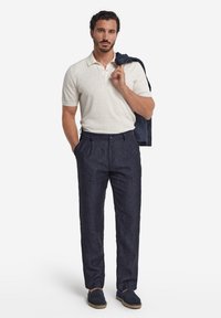 Ljusbeige pikétröja, marinblå linnebyxor och marinblå espadrillos. Slät textur, skräddarsydd passform och subtila detaljer på byxorna.