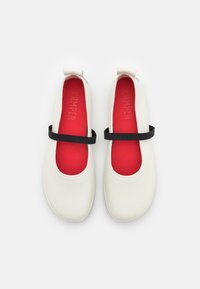 Ballerines en cuir blanc avec un bout arrondi, une bride élastique noire et une semelle intérieure rouge vif ornée d'un logo embossé.