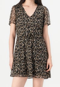 Robe à manches courtes et col en V noire avec un imprimé animal beige et marron. Elle présente une taille cintrée et un tissu léger et fluide.