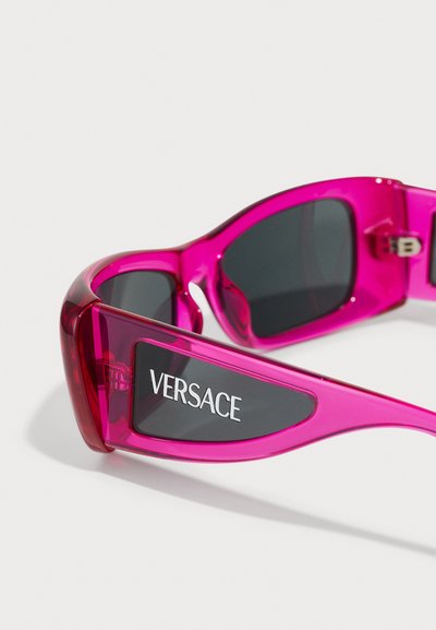 Roosa plastikust prillid tumedate läätsedega. Omavad julget, moodsa disaini ning Versace brändimist küljepeal. Sile tekstuur, sportlik kuju.