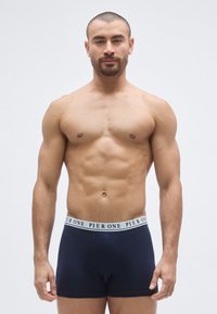 Σκούρα μπλε ανδρικά εσώρ ουχα boxer με λευκή μέση που φέρει το κείμενο "PIER ONE". Το ύφασμα φαίνεται μαλακό και ελαστικό, εφαρμοστό στο σώμα του μοντέλου.