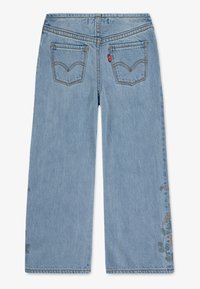 Světle modré džíny s širokými nohavicemi, které mají dvě zadní kapsy, dekorační květinovou výšivku na levé nohavici a kontrastní švy.