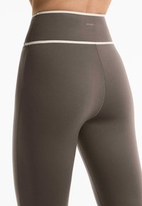 Hochgeschnittene Leggings in Dunkelgrau mit kontrastierenden hellgrauen Akzenten. Glattes, dehnbares Material mit enganliegendem Schnitt und OYSHO-Branding.