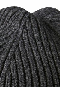 Gestrickter grauer Wollstoff mit ausgeprägten vertikalen Rippungen, weicher Textur und einem leicht unregelmäßigen, abgerundeten Rand oben.