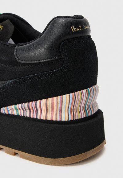 Sneaker in suede nero con tacco, dotato di un'accensione in tessuto a righe nei colori pastello e di un pannello in pelle nera testurizzata. Suola in gomma marrone.