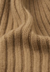 Beige ribbed knit fabric with soft texture, featuring vertical lines and a slightly fuzzy appearance, ideal for garments or accessories.