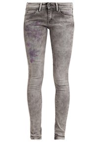 Jeans skinny de denim gris con un acabado desgastado, que presentan detalles florales morados en el muslo izquierdo. Diseño clásico de cinco bolsillos con herrajes metálicos.