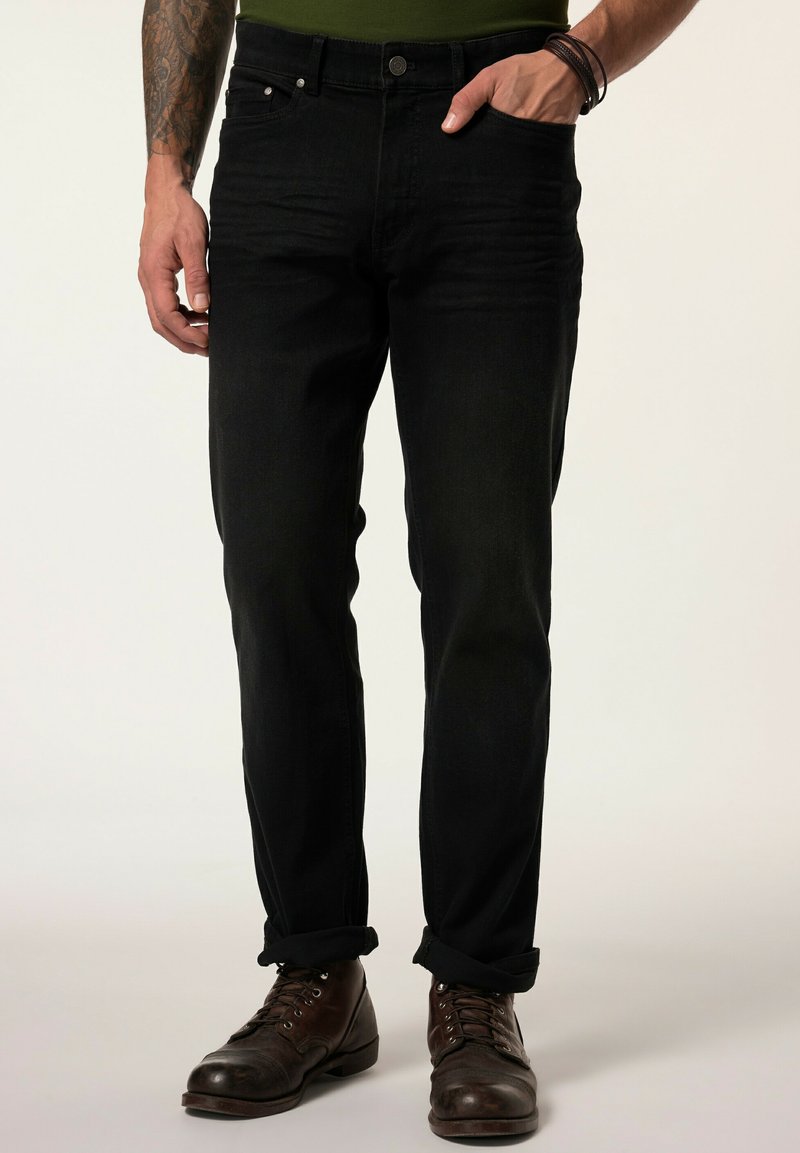 Jeans de mezclilla negra con corte recto, diseño de cinco bolsillos y un ligero desgaste, combinados con botas de cuero marrón.