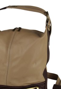 Leren handtas met een beige hoofdkleur en bruine accenten, voorzien van opvallende stiksels en metalen details. Ritssluiting aan de bovenkant.