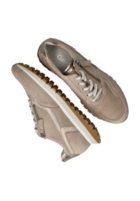 Sneaker in suede beige con suola in gomma testurizzata, dotati di lacci bianchi, una cerniera laterale e sottili accenti metallici.