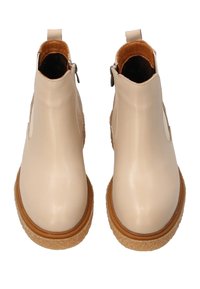 Beżowe skórzane botki za kostkę z okrągłym noskiem, teksturowaną beżową podeszwą i bocznymi zamkami. Pętla z tyłu ułatwiająca zakładanie. Gładkie wykończenie.