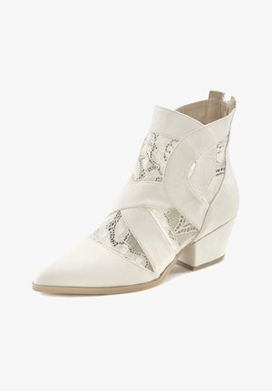 Bottine blanche à bout pointu, talon bloc, et panneaux en dentelle associés à des brides en tissu uni disposées en croix.
