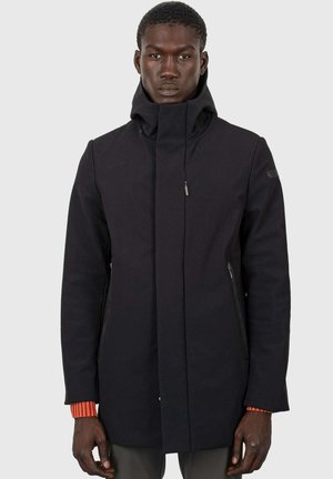 Cappotto nero con cappuccio, colletto alto, tasche con zip e finitura texture. Presenta polsini a maglia arancione a contrasto.