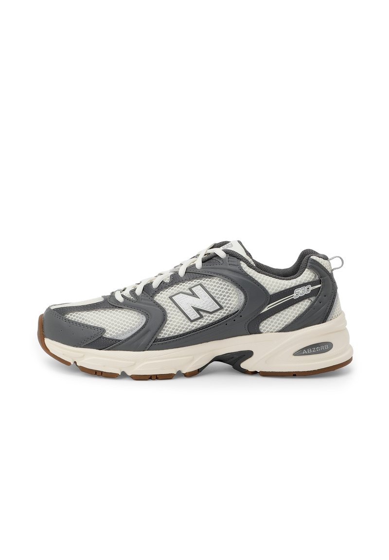 Šedé a bílé tenisky New Balance 530 s síťovanými panely, bílými tkaničkami, polstrovanou podrážkou a hnědou podrážkou, zobrazené v bočním profilu.