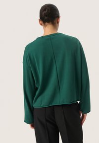 Groene, losse trui gemaakt van zacht materiaal, met een ronde halslijn, verlaagde schouders en een cropped lengte. Glad textuur en minimale naden.
