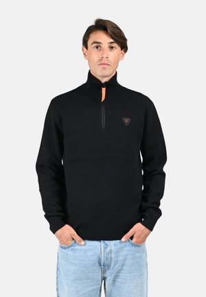 Sweater noir à col zippé en tissu tricoté, avec un zip orange et un patch logo triangulaire sur la poitrine. Conception ajustée.