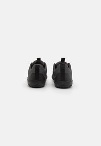 Sneaker neri realizzati con materiali in mesh e gomma, dotati di un colletto imbottito e di una linguetta per il controllo, suola testurizzata e design minimalista.