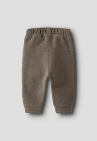 Pantalon bébé en tricot marron avec taille élastique et chevilles côtelées, étalé à plat sur un fond gris clair.