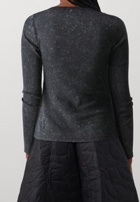 Maglietta a maniche lunghe in tessuto a coste grigio scuro con una leggera trama e un taglio casual, caratterizzata da un collo rotondo e un sottile motivo strappato.