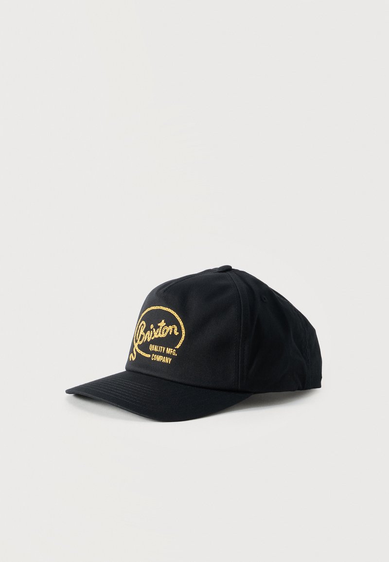 Μαύρο καπέλο μπέιζμπολ με κίτρινο κεντημένο λογότυπο "Brixton Quality MFG. Company" στο μπροστινό μέρος, εμφανιζόμενο σε απλό ανοιχτό φόντο.