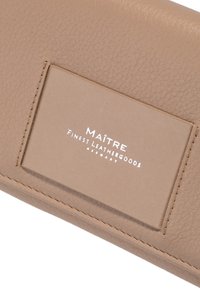Portafoglio in pelle beige con una finitura testurizzata, caratterizzato da una toppa con logo rettangolare e bordi cuciti con cura.