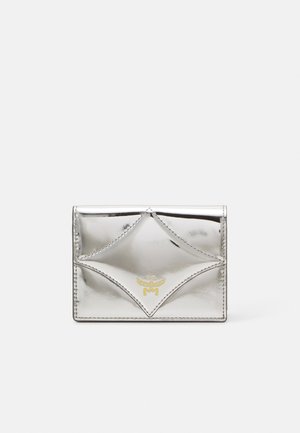 Porte-cartes en argent métallique avec un design en diamants cousus, comportant un petit logo doré au centre et une texture lisse et brillante.