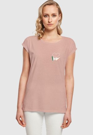 Light pink short-sleeve t-shirt with a round neckline and a small embroidered design featuring hands and a heart on the chest. Soft fabric.