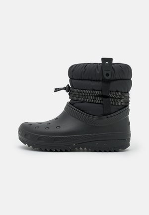 Black waterproof boot with a rounded shape, padded top, textured grip sole, and cord detailing at the ankle for adjustable fit.