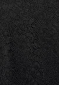 Tissu en dentelle noire avec des motifs floraux délicats et diverses textures en mailles créant un design élégant.