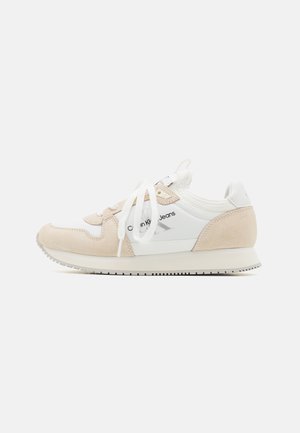 Sneaker blanche et beige avec des lacets blancs, des accents en suède et le logo "Calvin Klein Jeans" sur le côté, présentée sur un fond uni.