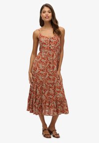 Sukienka maxi w rdzawoczerwonym kolorze z białym wzorem paisley. Ramiączka na cienkich paskach, detal z guzikami z przodu i rozszerzający się dół. Lekki materiał.