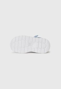Des chaussures bleu clair avec une semelle blanche texturée présentant un motif de tread profond. La semelle a une légère voûte et des bords arrondis pour le soutien.