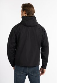 Sort vandtæt jakke med høj krave og elastiske cuffs, der har en glat mat finish og en afslappet pasform. Bagudsigten viser syningerne.