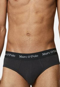 Schwarze Baumwollslips mit einem elastischen Bund, der mit weißem "Marc O'Polo" Branding versehen ist. Der Stoff ist glatt und enganliegend, designed für Komfort.