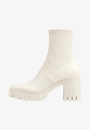 Hvid læderankelstøvle med tætsiddende skaft, chunky blokhæl, riller på sålen og sømløst design. Har minimal syningsdetalje.