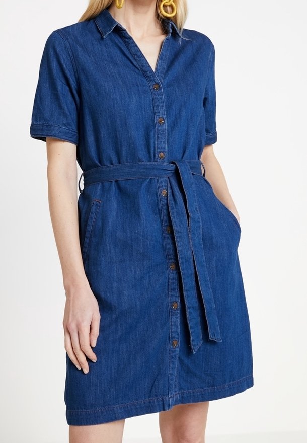 Sukienka zapinana na guziki z denimu w głębokim niebieskim kolorze, z krótkimi rękawami, paskiem w talii oraz bocznymi kieszeniami. Posiada kołnierzyk i prosty dół.