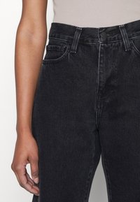 Sorte høy midje jeans laget av denim, med front knappelukking, to sidelommer og synlig kontraststing.
