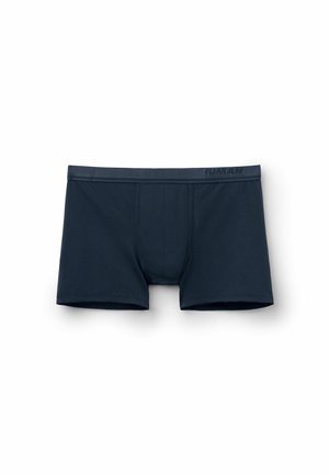 Boxers en bleu marine fabriqués en tissu doux, présentant un design ajusté avec une couture horizontale et un logo discret sur la ceinture.
