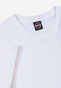 Λευκό βαμβακερό T-shirt με στρογγυλή λαιμόκοψη και μαύρη ετικέτα "Colmar Originals" ραμμένη μέσα στο γιακά.