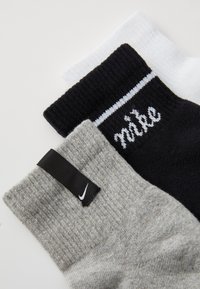 Trei perechi de șosete: albe, negre cu o dungă albă și "nike" scris cursiv, și gri cu un etichetă logo negru. Material texturat, lungime standard.