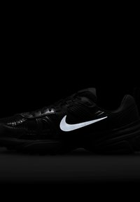 Crne atletske cipele s gornjim dijelom od mrežastog i sintetičkog materijala, s istaknutim reflektirajućim bijelim Nike swooshom i teksturiranom jednom.
