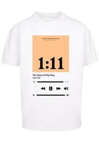 Fehér pamut póló, amelyen egy nagy, barack színű négyzetgrafika található, fekete felirattal "1:11" és alatta lejátszási vezérlők.