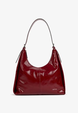 Sac à bandoulière en cuir rouge profond brillant avec une seule sangle large et un petit logo "nat & nin" en bas à droite.