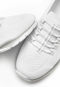 Scarpe sportive bianche con un upper in tessuto lavorato a maglia, superficie testurizzata e lacci elastici. Presentano una suola in gomma trasparente e una punta rinforzata.
