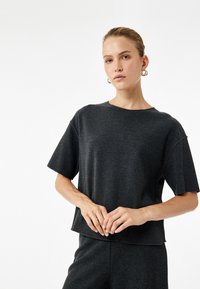 Dunkelgraues, verkürztes T-Shirt aus weichem Stoff, mit Rundhalsausschnitt und kurzen Ärmeln, entspannt geschnitten und mit minimalen Nähten.