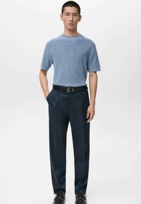 Jasnoniebieski, krótki rękaw, sweter z teksturowanym splotem, zestawiony z granatowymi eleganckimi spodniami i czarnym paskiem. Spodnie mają prosty krój i delikatny połysk.