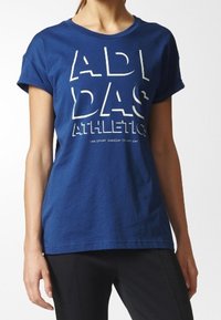 Blå bomulls t-shirt med korta ärmar, med en vit grafisk utskrift som står "ADIDAS ATHLETICS" på framsidan.