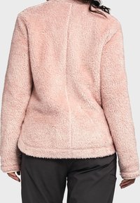 Różowa, puszysta kurta polarowa o teksturowanej powierzchni, zaokrąglonym dolnym brzegu i długich rękawach. Charakteryzuje się czystym, prostym wzornictwem bez widocznych elementów metalowych.