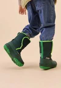 Grüne wasserdichte Stiefel mit einer strukturierten grünen Sohle und leuchtend grünen Akzenten, ausgestattet mit einem hohen, weichen, gepolsterten Schaft für Isolierung und Komfort.